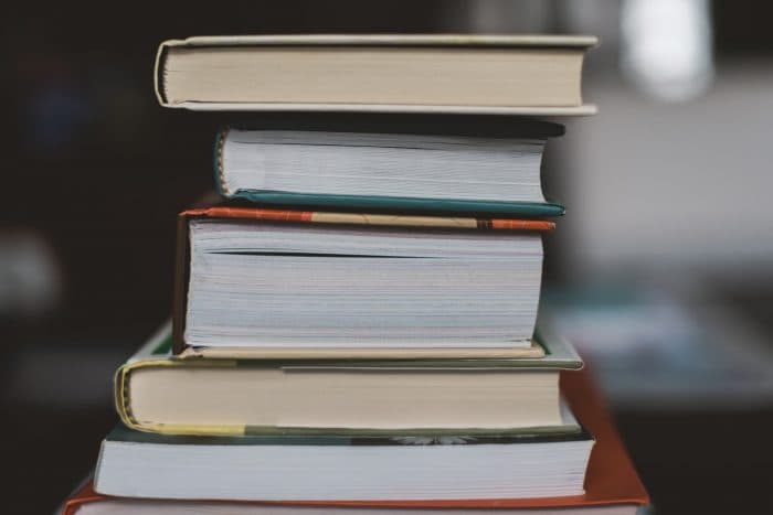 A stack of books on a wooden table, from Chris’s article about writing The Money Tree.